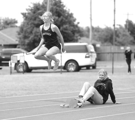 ABBIE MYERS goes through her warmup routine while Adlee Friesen holds the blocks as Myers prepares to run the first leg of the 4x400 meter relay during last Friday’s conference track meet. Myers and her teammates placed third in the event and overall in KHS fares well against tough conference foes