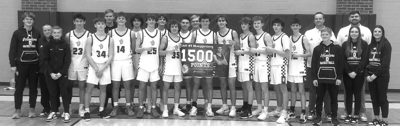 JETT MUEGGENBORG and his Okarche teammates commemorate the Warrior junior surpassing 1,500 career points during his team’s victory over Hennessey last week. Mueggenborg scored 39 points and grabbed 13 rebounds. [Photo provided]