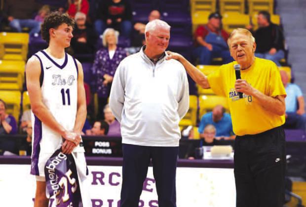 FORMER OKARCHE coach Tom Arms, right, addresses the crowd after Tuesday night’s Warrior win against Turpin in which Jett Mueggenborg, left, set the school’s all-time scoring record. He broke the mark of Barry Schwarz, center, who was coached by Arms. 
