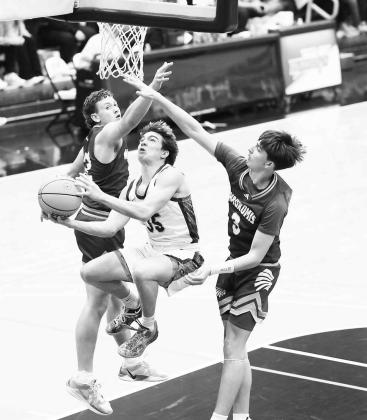 OKARCHE SENIOR guard Colin Hendrickson makes an acrobatic move to split two defenders as he scored during the first half of the Warriors’ area title win. [KT&amp;FP Staff Photo]