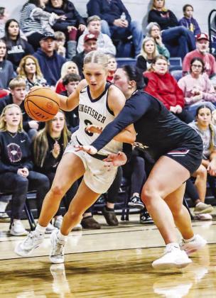 KINGFISHER’S ABBIE MYERS drives by Weatherford’s Payton Mills during the first half of Wednesday night’s championship game. Myers finished with 19 points to help lead her team to the title. [Photo by Chris Simon/www.simon-sports-photos. smugmug.com]