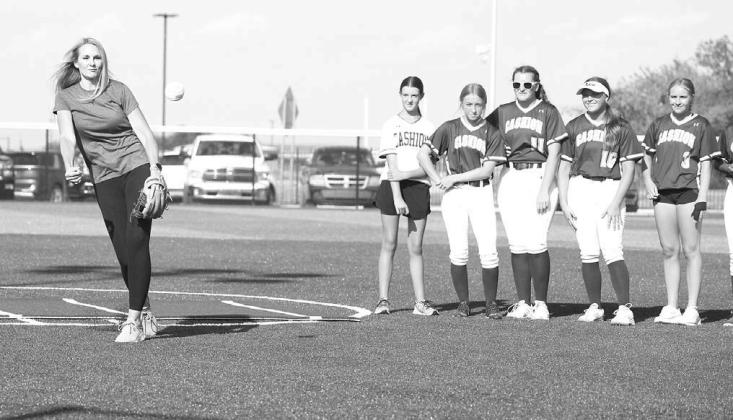 STILL GOT IT – Linzee (Roby) Beaman delivers the first pitch as members of the Cashion softball team look on Monday. Cashion was opening its newly-renovated softball complex, which included new turf. Beaman was on Cashion’s first-ever fastpitch team a