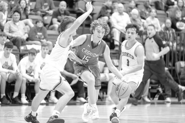 CASHION’S Austin Frazier (15) splits a pair of Hooker defenders during his team’s Class 2A area championship win last Friday in Hennessey. Frazier scored 15 to lead Cashion, which qualified for the state tournament for a third straight year. [Photo by Cashion celebrates area title, sets sights on state