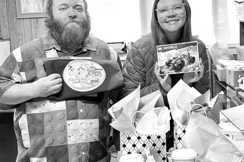 FOOD AND PRIZES – Hennessey Public Library Director Steven Mitchell and Children’s Librarian Macee Smith show off a few of the door prizes to be given at the Friends of the Library’s annual fundraiser Saturday, Feb. 7, at the Hennessey High School c