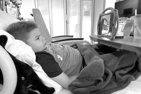 WRAY FAMILY – Pictured together are members of the Wray family: Parents Phil and Wendy along with Wilder, 7, and Scout, 4. On the right is a much-improved Wilder catching up on some shows in his hospital room. [Photos provided]