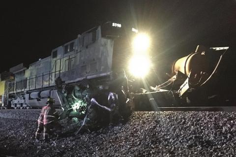EMERGENCY WORKERS clear wreckage from the Union Pacific tracks south of Kingfisher Sunday night after the train collided with a saltwater disposal truck, ejecting and killing the driver. [TIMES-FREE PRESS Staff Photo]