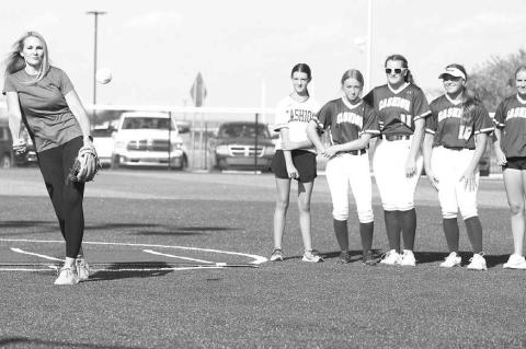 STILL GOT IT – Linzee (Roby) Beaman delivers the first pitch as members of the Cashion softball team look on Monday. Cashion was opening its newly-renovated softball complex, which included new turf. Beaman was on Cashion’s first-ever fastpitch team a