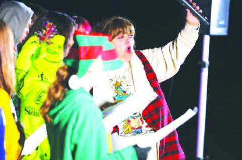 KINGFISHER PARK lit up Saturday night at the opening of Kingfisher Winter Nights. On the bottom left is one of Santa’s Elves which directs State Highway 33 traffic where to turn into the park. On the bottom right is KPS Choral Director Diann Magnus help