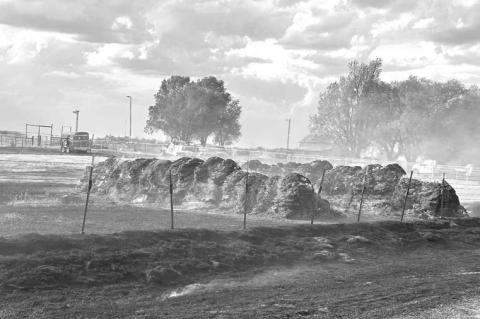 HAY FIRE – Hennessey fi refi ghters successfully work to keep fl ames away from the Heather Hawk home at about 4:30 p.m. Saturday. The family farm is located one mile south of Lacey and one mile east. The fi re was caused due to blown fuses on OG&E lines after a trackhoe two miles away hit a power line, according to Hennessey Fire Chief Brandon Scott. The fi re burned about 15 acres of farm land and 22 hay bales. [Photos courtesy of Heather Hawk]