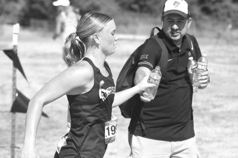 WATER IS BETTER – Kenny “Bobby Boucher” Lunsford hands off a bottle of water to Scout Snodgrass as she’s running the pre-state meet. Runners competed in temperatures in the mid- to upper-90s during the meet. [KT&FP Staff Photo]