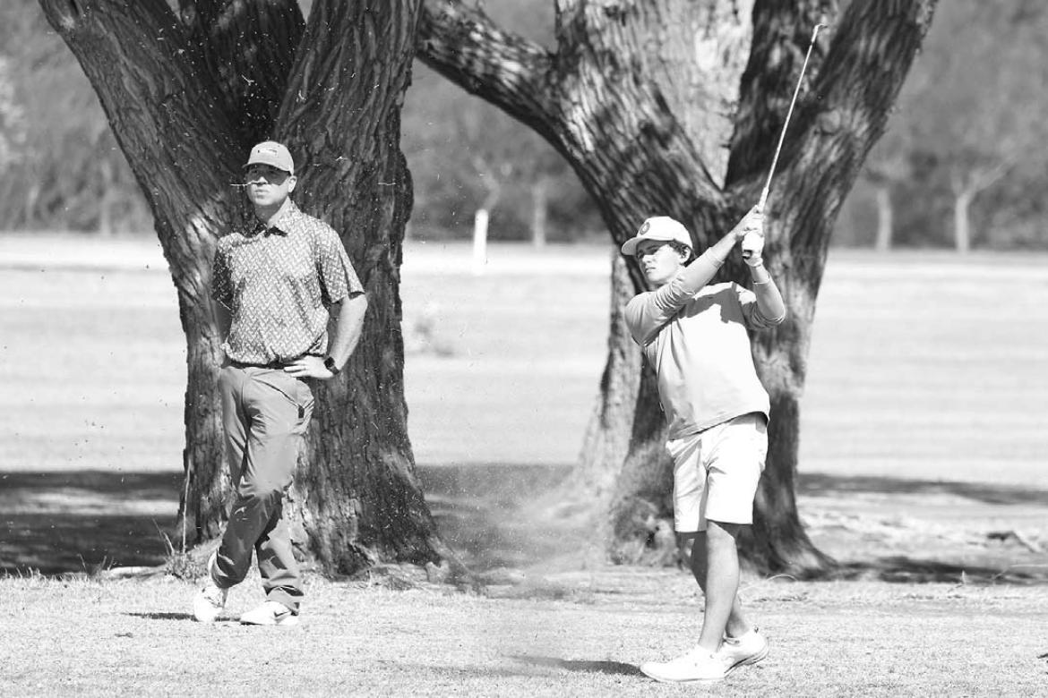 OKARCHE GOLF coach Adam Wilczek watches Cy Collamore’s approach shot on the second hole of the Dover Small School Invitational on Monday. Collamore shot a 74 and finished fourth in the tournament, just his second competition round for Okarche. [KT&amp;F
