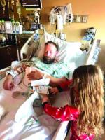 MATT SCOTT lays in a hospital bed after nearly 12 hours of surgery on Christmas Eve as his 6-year-old daughter Charlie opens gifts. [Photo provided]