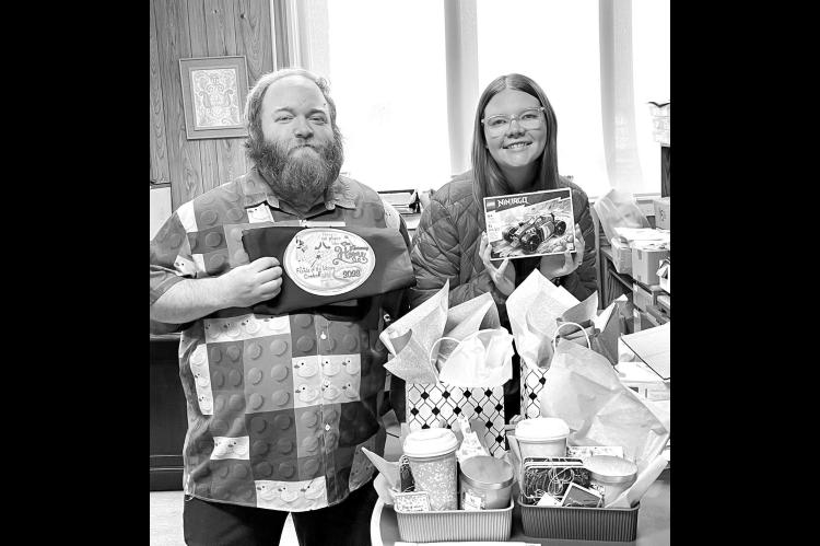 FOOD AND PRIZES – Hennessey Public Library Director Steven Mitchell and Children’s Librarian Macee Smith show off a few of the door prizes to be given at the Friends of the Library’s annual fundraiser Saturday, Feb. 7, at the Hennessey High School c