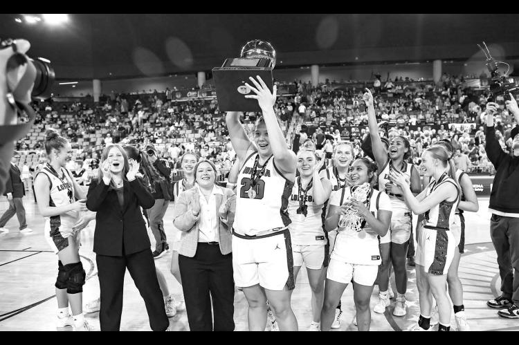 NUMBER 17 – Lomega players and managers celebrate as Kinsley Fisher raises the 2026 Class B-II gold ball to acknowledge the Raider faithful in the crowd. The Lady Raiders won their 17th title with a 71-44 win over Leedey on Saturday. Hadley Ott, below left, lets loose with one of her seven made 3-pointers in the game. Aliana Lawson, below right, pushes the pace, a strategy that helped Lomega wear down Leedey early in the game. [Photos by Chris Simon/www.simon-sports-photos.smugmug.com]