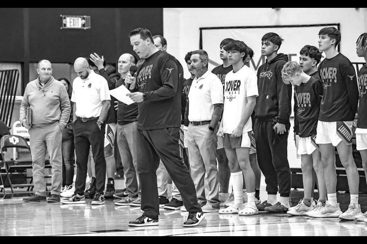 DOVER BOYS coach Jared Reese reads a message during a ceremony Tuesday at UCO outlining all the people who helped save the life of Randy Vitales (black sweatshirt) after the DHS sophomore collapsed during a a game. Dover honored all of those who offered h