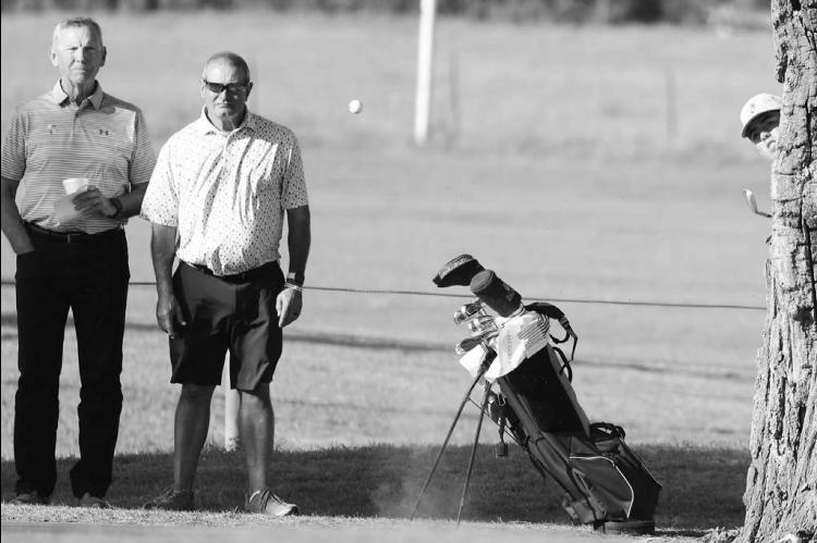 TOURNAMENT OFFICIALS Doug Jech and Gary Wilson look on as KHS freshman River Roof peeks from behind a tree to watch the result of his punch shot on the sixth hole during Monday’s regional. Below right, Luciano Orozco watches his chip shot on the 17th hole of one of his rounds. [KT&amp;FP Staff Photos]
