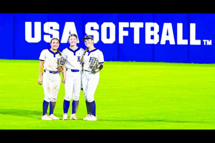 KHS OUTFIELDERS, from left, Liliana Garramone, Kendall Farrar and Callie Blair stop for a quick photo between innings as they played Thursday night on the main field at Devon Park, which hosts several national and international softball events, including the Women’s College World Series. KHS beat Noble 6-0 in the game. [Photo by Chris Simon/ www.simon-sports-photos.smugmug.com]