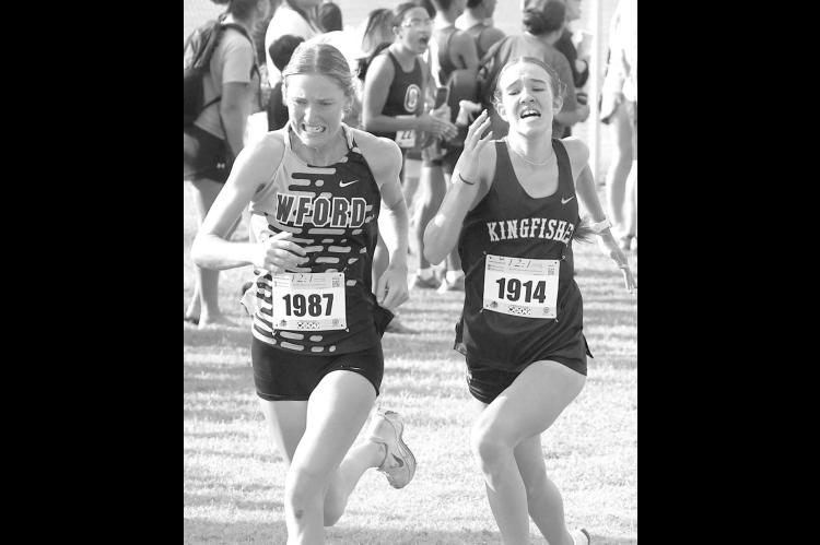 KHS JUNIOR Addison Price and Weatherford’s Cora Hamons battle for position down the stretch at last Saturday’s Sand Plum Invitational. Hamons edged Price at the finish line as the pair were fifth and sixth, respectively. However, Price’s KHS team do