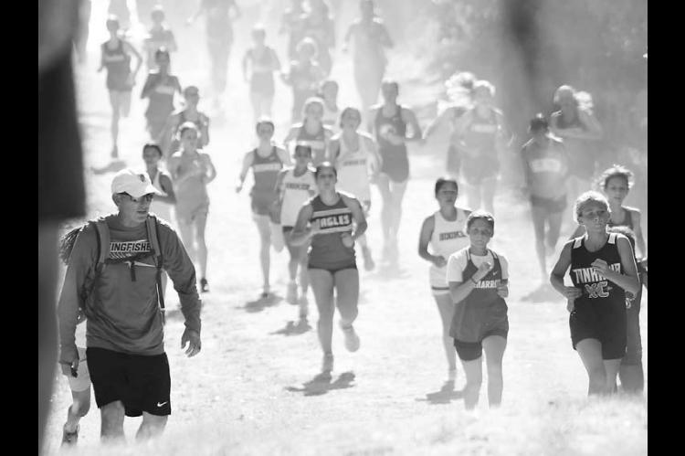 NO LAZY WEEKEND STROLLS ALLOWED – The sun was shining down and the dust was rising up on a particularly hilly part of the Watonga Cross Country Meet last Saturday. Kingfi sher coach Stefan Seifried (left) encourages runners as they make their way through the course. For results of the meet, see Pages 7 and 10 inside this edition.