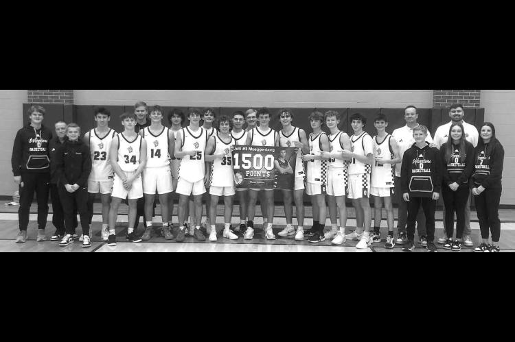 JETT MUEGGENBORG and his Okarche teammates commemorate the Warrior junior surpassing 1,500 career points during his team’s victory over Hennessey last week. Mueggenborg scored 39 points and grabbed 13 rebounds. [Photo provided]