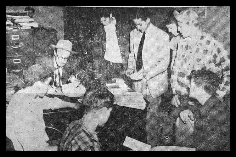 James Crane, chamber of commerce president, signs checks to boys who sold animals in the junior stock show auction Monday night. Bill Rogers, C-C Secretary, and a number of exhibitors are onlookers.
