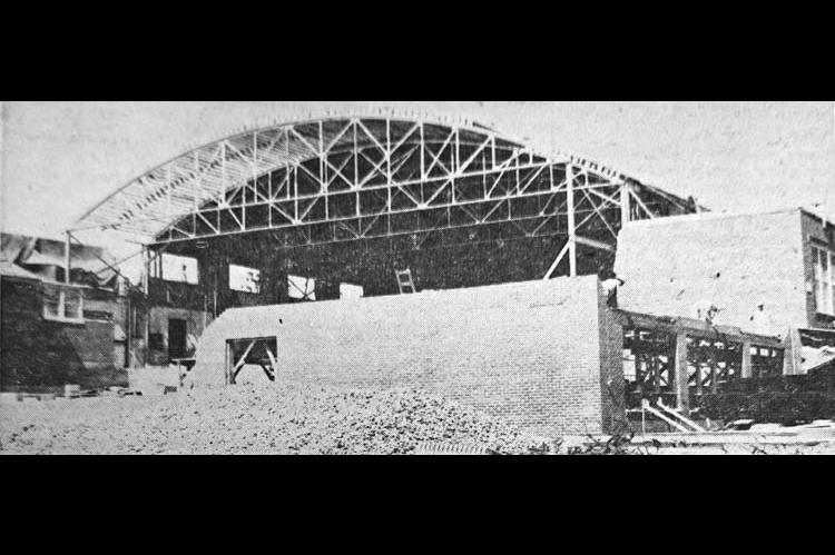 Pictured is Dover School. The roof of the gymnasium is being extended westward for a larger court, and bleachers on the north and south to seat 1,000 persons. A corridor on the east end of the gymnasium will close it off from the classrooms. Locker rooms will be established under the bleachers, and at the west end of the gymnasium will be a large stage, with a classroom under it. The southwest wing of the building is being extended for additional classrooms. (Free Press, July 9, 1951)