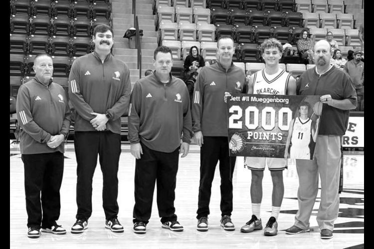 RARE AIR – Okarche’s Jett Mueggenborg, second from right, eclipsed 2,000 career points on Saturday as the Warriors improved to 3-0. He’s holding a banner to commemorate the milestone along with Okarche Superintendent Josh Sumrall, far right. Also pi