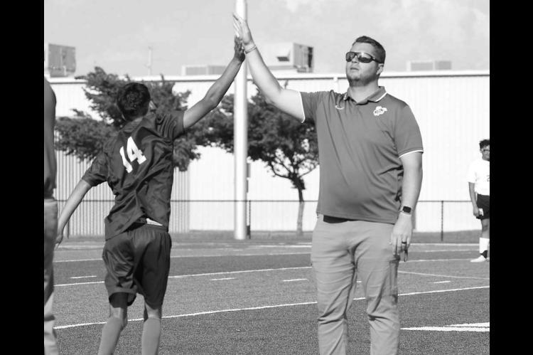 KHS ALUM Isaac Waltman (right) high-fives senior Bryan Campos as Campos prepares to take the field. Waltman has been the head soccer coach for five seasons, but is leaving KPS to become an assistant principal in Enid. [KT&amp;FP Staff Photo]