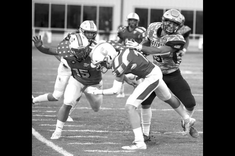 KINGFISHER RUNNING BACK Cade Stephenson (far right) tosses Chisholm’s Nick Deterding out of his path en route to a 55-yard touchdown run during last week’s game. Stephenson scored four Tds in the KHS win. [Photo by KHS Photography/www.khsphotography.smugmug.com]