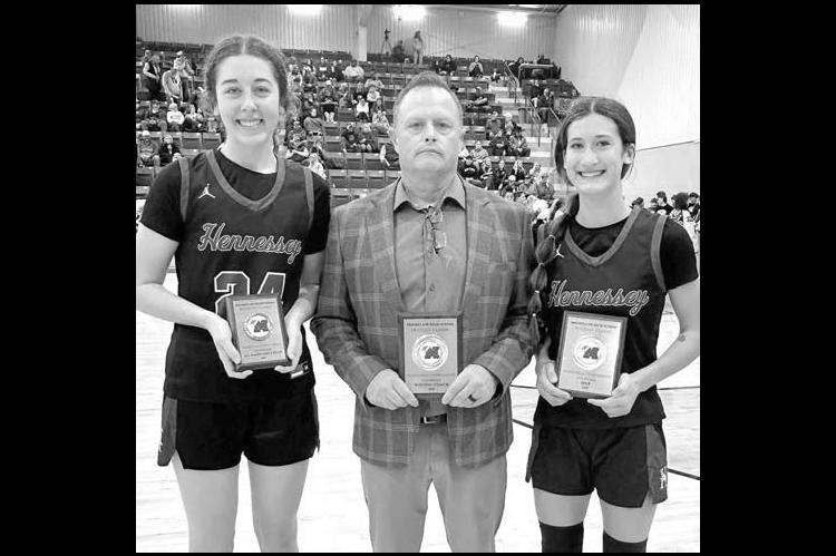 HENNESSEY’S Emma Copeland (right) was the MVP and Clare Munroe (left) joined her on the all-tournament team at Mooreland. They’re joined by their coach Brian Richardson after claiming the championship. [Photo provided]