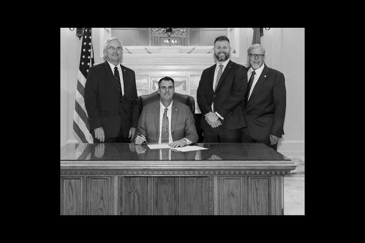 BILL SIGNING – Fom left, Sen. Darcy Jech, R-Kingfisher, Gov. Kevin Stitt, Justin Wolf, chief administrator of communications and government relations for DOC, and Rep. Carl Newton, R-Cherokee at a ceremonial bill signing for SB 1456, aimed at addressing staffing shortages in DOC.