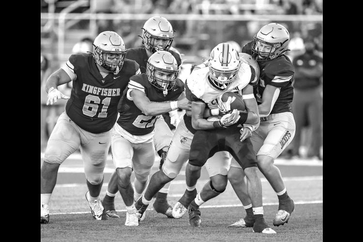 KINGFISHER DEFENDERS, from left, Donovan Dunn, Jayzen Surveyor, Eduardo De La Torre (behind ball carrier) and Camden Weinmeister swarm to the ball during the first half. Pictured on the left is senior Carter Stephenson going up for one of his three catches on the night, which totaled 90 yards. On the right is Drew Snider powering through the grasp of Clinton’s Parker Turney as he scored on a 37-yard touchdown run in the first quarter. [Photos by Chris Simon/www.simon-sports-photos.smugmug.com]