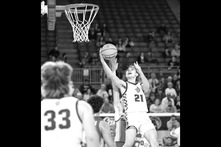 OKARCHE’S Hunter Mueggenborg makes a move to the basket during the Warriors’ quarterfinal win Tuesday morning. Mueggenborg scored 11 points and had eight assists in the game. [Photo by Russell Stitt/www.stitt.smugmug.com]