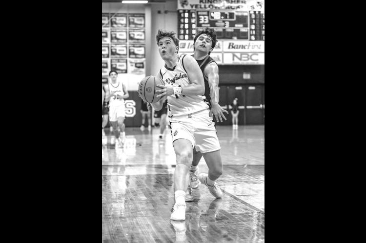 HAYES WHITE drives to the bucket during the third quarter of Kingfisher’s 66-60 double- overtime victory Thursday against Cushing. White scored 30 points for the Jackets as they advanced to the regional championship. [Photo by Chris Simon/www.simon-spor