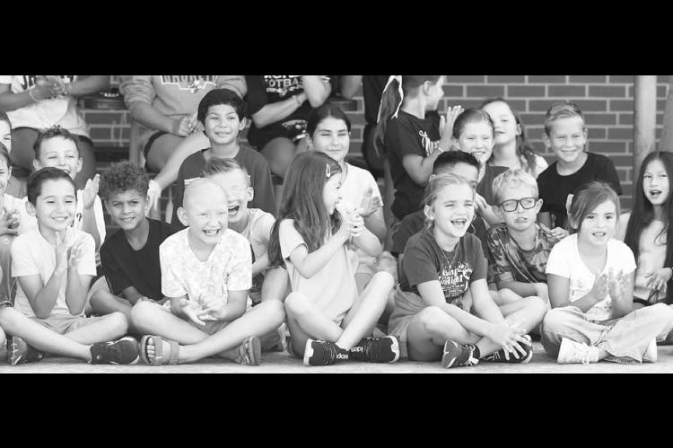 KINGFISHER HERITAGE Principal Lisa Meier bends down to kiss a pig on Monday, a promise she made to her students if they met a fundraising goal. The students, pictured right, mostly screamed their approval while a few did look on with a bit of a cringe. [KT&FP Staff Photos]