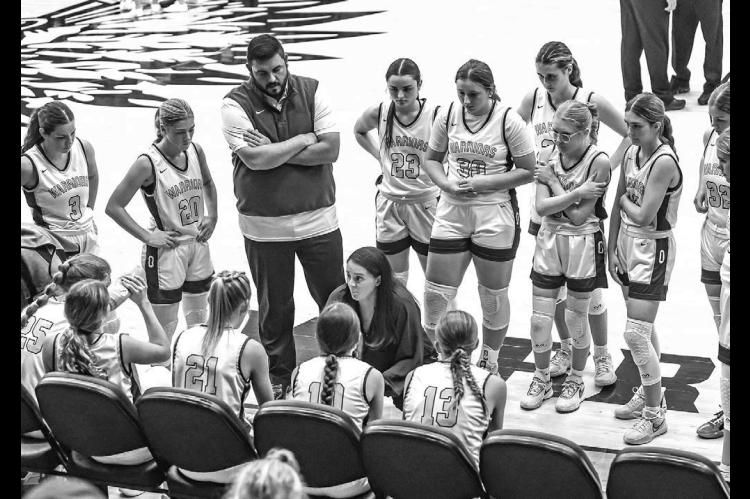 NEW OKARCHE girls coach Brett Tahah talks to her team during a timeout as her husband and assistant coach Scott Tahah and the rest of the Lady Warriors listen in during last Friday’s game. [Photo by Chris Simon/www.simon-sports-photos. smugmug.com]