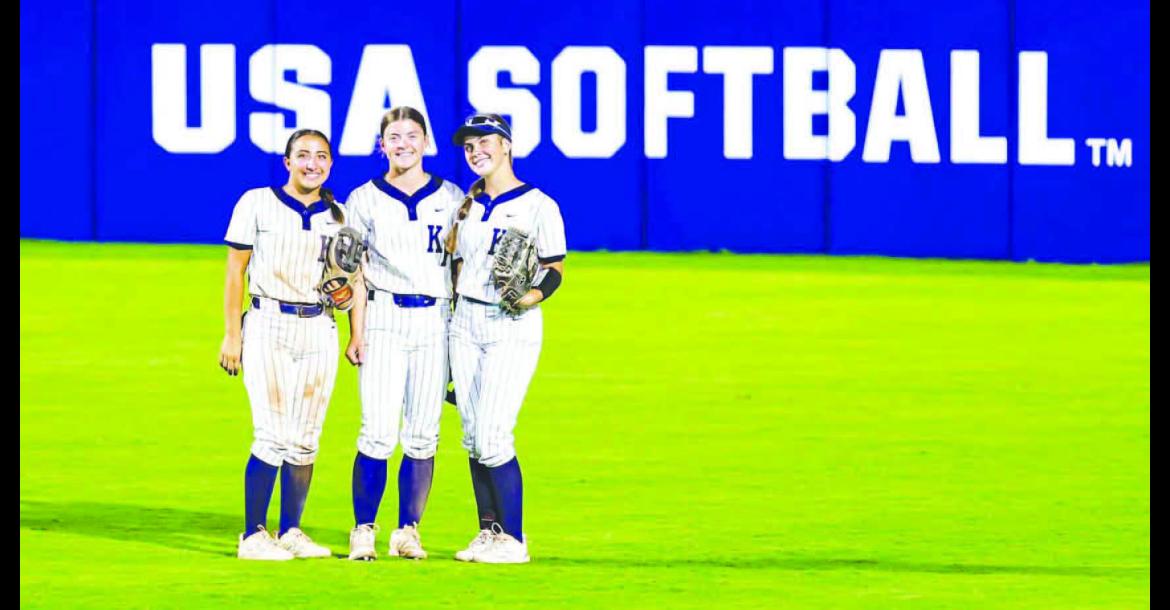 KHS OUTFIELDERS, from left, Liliana Garramone, Kendall Farrar and Callie Blair stop for a quick photo between innings as they played Thursday night on the main field at Devon Park, which hosts several national and international softball events, including the Women’s College World Series. KHS beat Noble 6-0 in the game. [Photo by Chris Simon/ www.simon-sports-photos.smugmug.com]