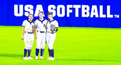 KHS OUTFIELDERS, from left, Liliana Garramone, Kendall Farrar and Callie Blair stop for a quick photo between innings as they played Thursday night on the main field at Devon Park, which hosts several national and international softball events, including the Women’s College World Series. KHS beat Noble 6-0 in the game. [Photo by Chris Simon/ www.simon-sports-photos.smugmug.com]