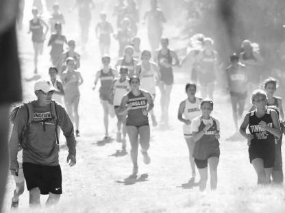 NO LAZY WEEKEND STROLLS ALLOWED – The sun was shining down and the dust was rising up on a particularly hilly part of the Watonga Cross Country Meet last Saturday. Kingfi sher coach Stefan Seifried (left) encourages runners as they make their way through the course. For results of the meet, see Pages 7 and 10 inside this edition.