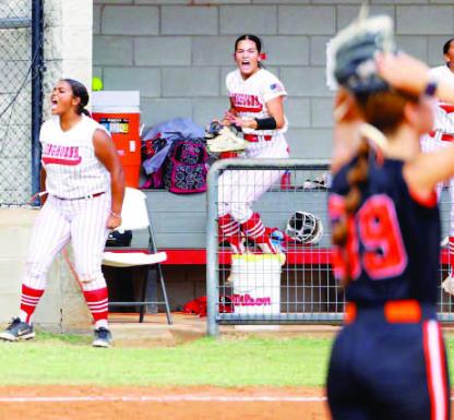 DOVER SOFTBALL’S Alexcea Caldwell, left, and Brooklyn Martin, right, celebrate in the dugout while the opposing pitcher offers up the “surrender cobra” during the sixth inning of the Lady Longhorns’ Class B district tournament game against Carney. The players are reacting to a big Dover hit in the inning, one in which the Lady Longhorns broke open a tie game with five runs en route to the win. For more on the game, see inside this edition. [KT&amp;FP Staff Photo]