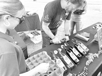 A FINE WINE FESTIVAL – The weather was just right last Saturday and about 600 people attended the 15th annual Hennessey Wine Festival. Brooklyn Harris watches as this Wild Horse Canyon wine vendor lines up his entries for the wine tasting judges. Harris is a former Hennessey High School student member of Hennessey United, which sponsors the event, and helped out at this year’s event. She is now a junior at Oklahoma State University. [Photo courtesy of Cash Macy]